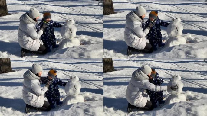 孩子在雪地里迈出了第一步，和妈妈一起散步。1岁的男婴在冬天学习与妈妈在公园散步。