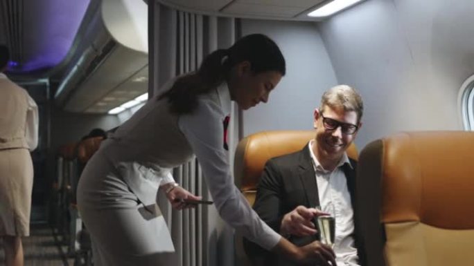 为商务旅客乘坐商务舱飞机提供饮料或香槟的空姐的4k视频片段。生活中的小奢侈品。