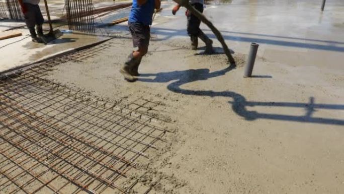 装配工，工人拿着泵软管将新鲜混凝土浇筑到钢筋上的建筑地基中