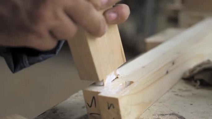 慢动作。木匠的特写镜头将两个螺丝夹拧紧到一块轻木头上。专业木匠从木头上收集家具零件。在木工车间组装家