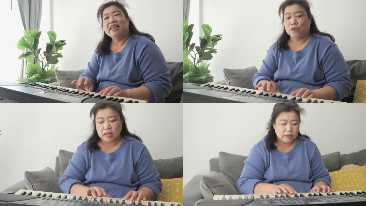 肥胖的亚洲成年妈妈在家学习在靠近窗户的沙发上弹奏键盘乐器，生活方式理念。