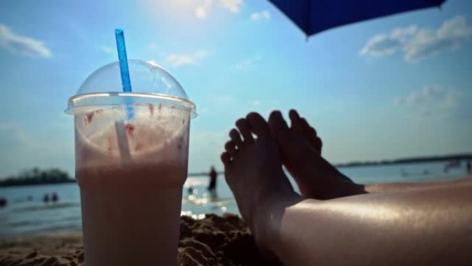 沙滩背景上的奶昔和女性腿