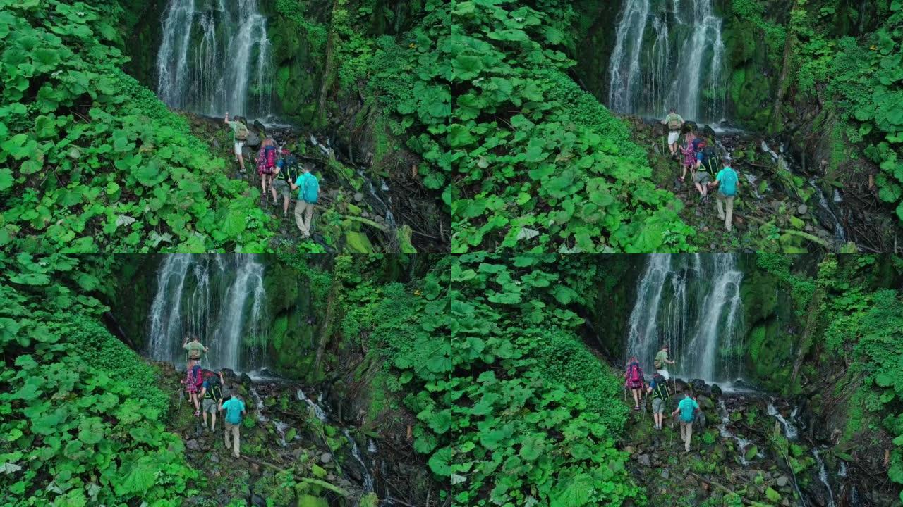 四名游客从高处坠落，河道上到处都是倒下的树木和大石头。团队和瀑布的空中无人机视图