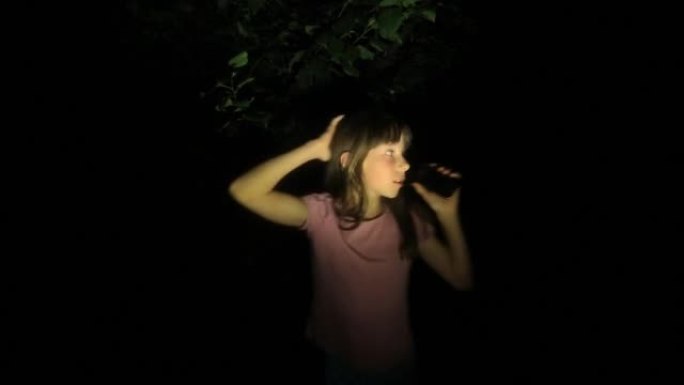 受惊的小女孩，尖叫着呼救，试图通过电话联系父母。这个孩子晚上在森林里迷路了