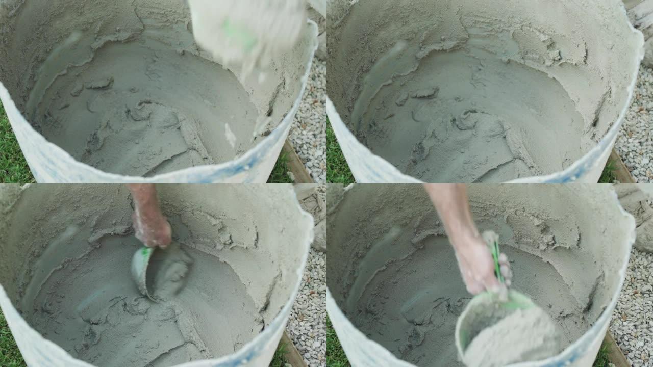 工人将水桶中的混凝土混合物混入石膏砖墙，进行家庭装修