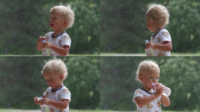 Little child drinking water from a baby bottle in 