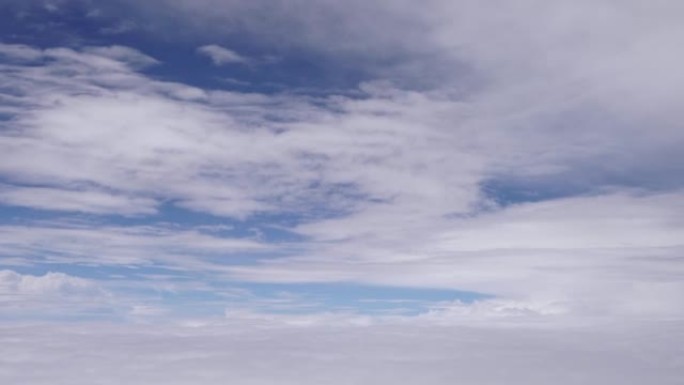 飞机窗户的鸟瞰图，它在白云之间飞来飞去，蓝天超过。