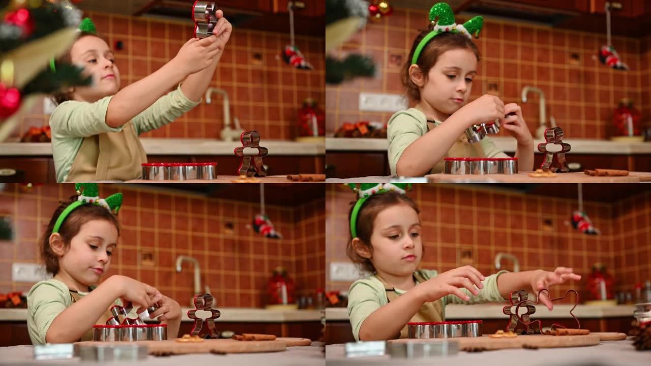 可爱的热情的小女孩穿着厨师围裙和精灵箍，在厨房玩饼干切割机，享受圣诞节的气氛。