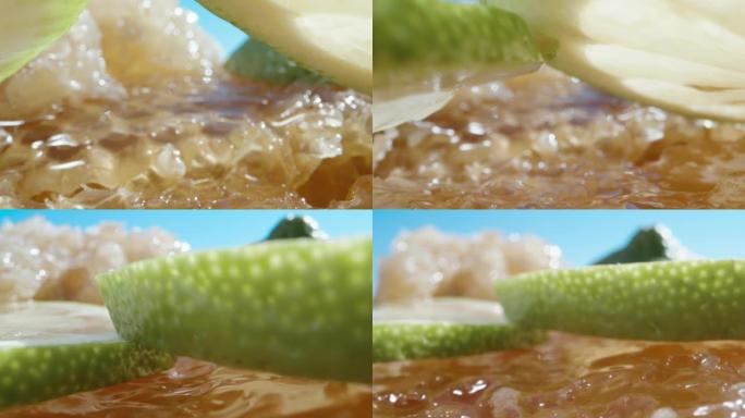 相机在蜂蜜上平移，从柠檬片下面经过。超级宏观幻灯片。