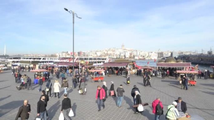 明诺努广场的人群。伊斯坦布尔城市的旧广场，有传统建筑、清真寺、人和海洋。埃姆诺努土耳其
