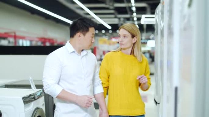 幸福的混血儿亚洲夫妇家庭男人和女人在超市调查选择新的家用电器冰箱冰箱冷却器，冷冻室