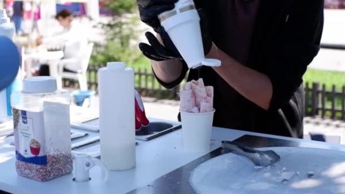 男人的手正在用syrop倒泰国冰淇淋。夏季甜点。