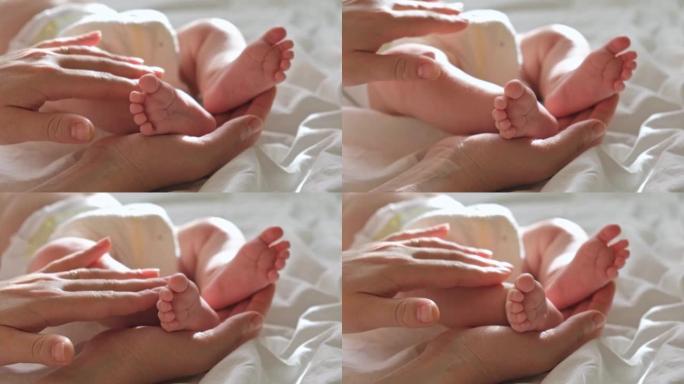 婴儿的脚在母亲的手中，在她的手掌上。快乐的父母抱着婴儿的脚，特写。生育，家庭，生育概念。女人触摸婴儿
