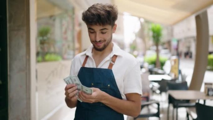 年轻的阿拉伯男子服务生在餐厅工作的钱