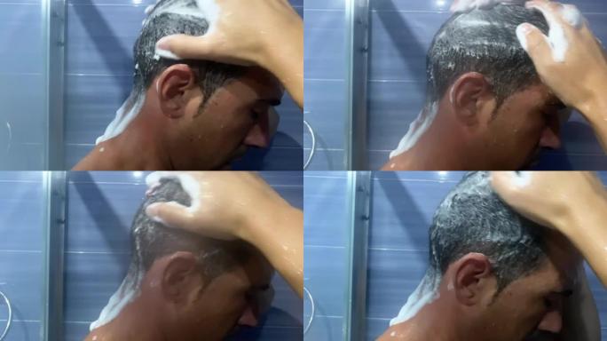 一个男人在浴室里揉着他的头发，用泡沫洗发露在上面起泡沫。一名年轻男子在淋浴时用泡沫抹头发的视频。