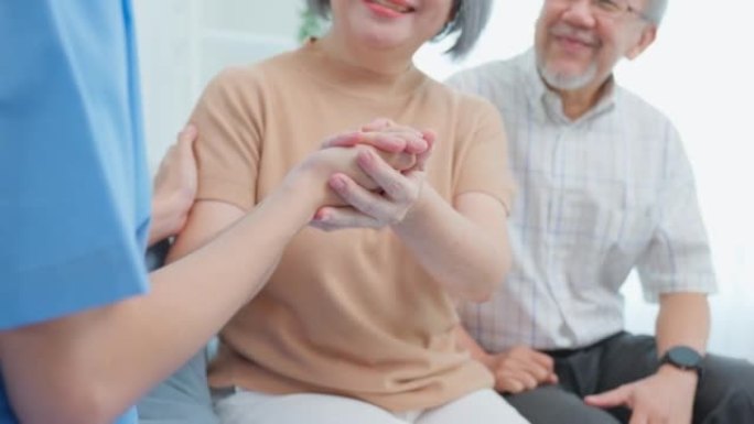亚洲护理护士在家检查高级女性患者和丈夫。有吸引力的年轻专业护理人员女性支持在家里的起居室里向老年成熟