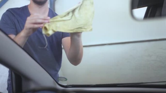 Male Looking At Car While Wiping Windshield And Dr