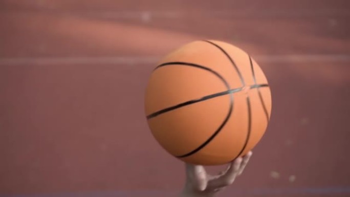 运动生活方式，年轻人的手试图用手指慢动作旋转的篮球来招数