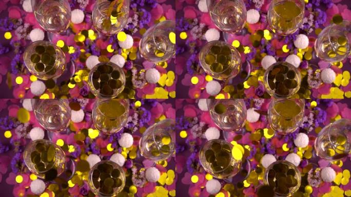杯中掉落的五彩纸屑配起泡酒，圆形糖果配椰子片，心形五彩纸屑和紫色背景上的花朵。慢动作。