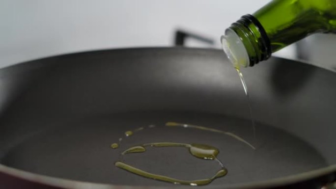 慢动作男子将橄榄油从瓶子倒入煎锅，特写镜头。宏观射击厨师将植物油倒入煎锅进行慢动作烹饪。烹饪特写。