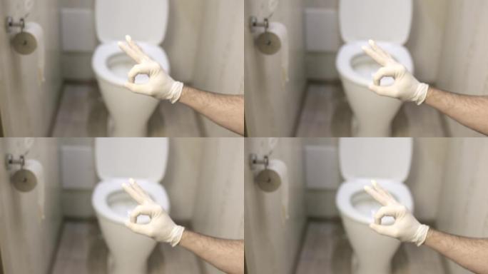 一名男子在厕所背景上的白色乳胶手套上显示OK