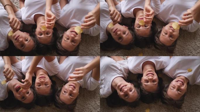 青少年姐妹女孩三胞胎有趣的坐着吃脆薯片扔和用嘴抓