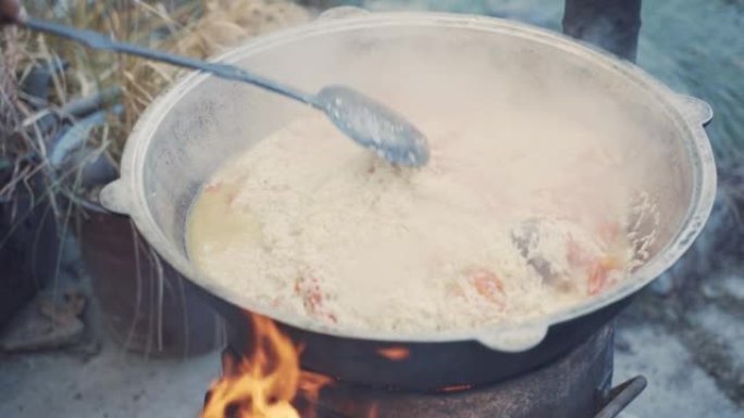 厨师用漏勺在锅里拌肉饭。
