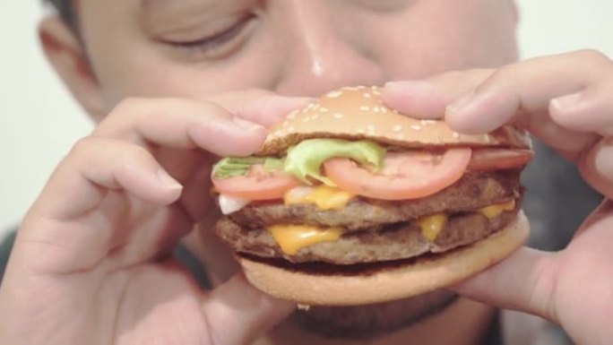 特写镜头喜欢吃汉堡的年轻人。享受不健康的饮食