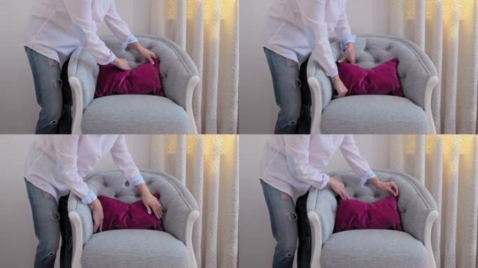 用天鹅绒粉色靠垫装饰蓝色扶手椅的女人