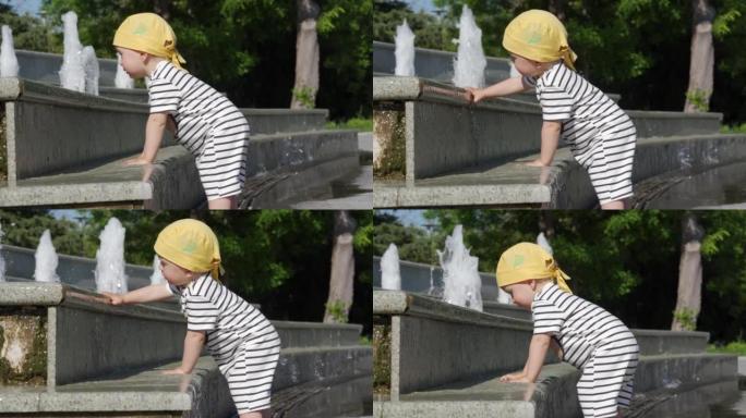 快乐的孩子在阳光明媚的夏日在公园的喷泉里玩得开心。1.5岁的孩子在热天玩喷泉水。