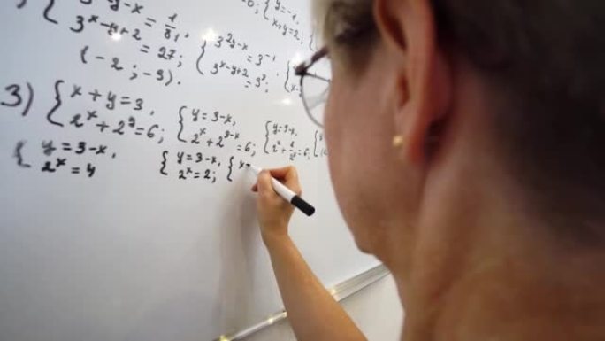 年老的老师正在白板上写方程式。