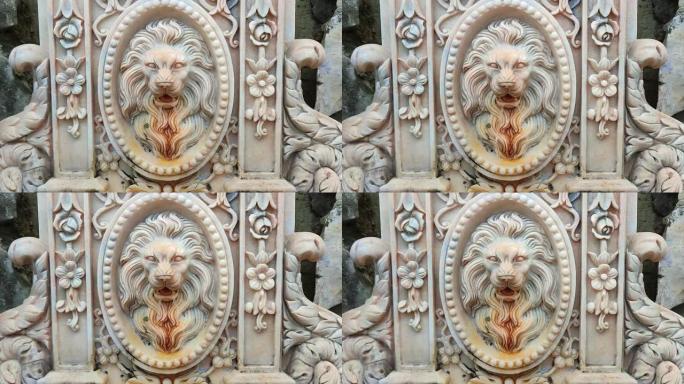 古老的白色大理石喷泉装饰着一只喷出水的狮子的头，带有古老纹理的童话中的宫殿装饰品