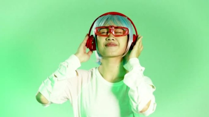 Metaverse音乐世界概念，年轻的亚洲女子戴着白色眼镜和红色耳机在绿色背景上听muusic和da