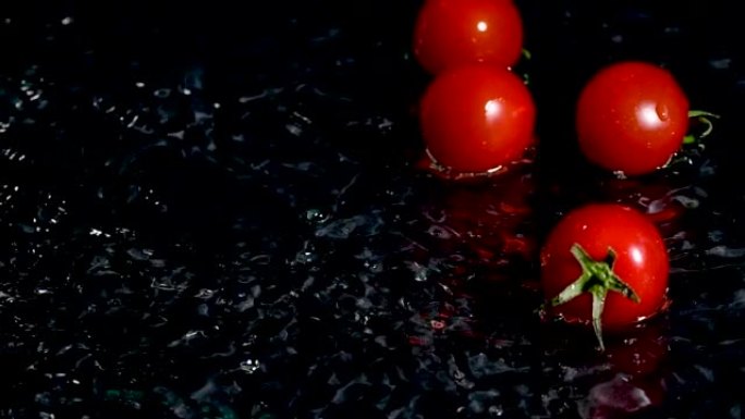 西红柿落入水中，黑色背景上有飞溅和气泡