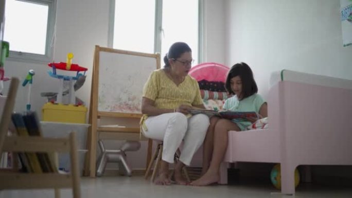 家庭-一名印度高级妇女在家里给她的两个种族孙子读一本书