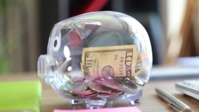 Glass piggy bank is refilled with coins and dollar