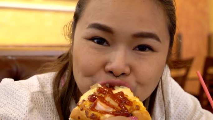 在商店里吃披萨的亚洲女性。