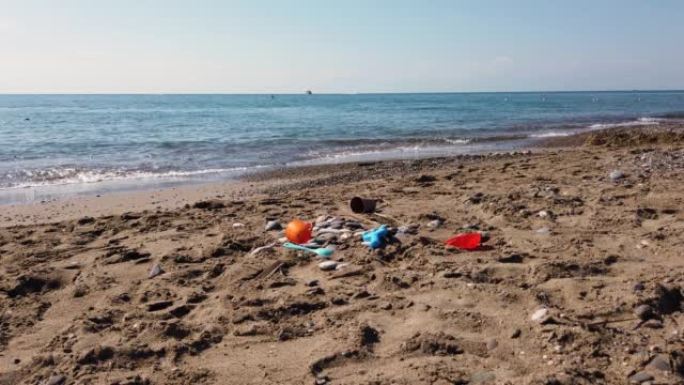 孩子们的塑料玩具散落在沙滩上。废弃的水桶和铲子在沙子里。海上旅游和休闲概念。