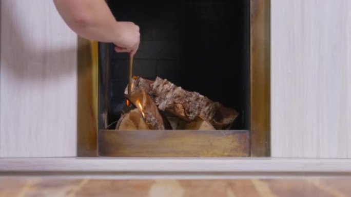 人用特殊的大火柴在壁炉里放火烧木头。
