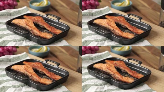 慢动作4k视频，烤烤鲑鱼片在黑色盘子上撒上欧芹草本和黑胡椒片。鲑鱼健康饮食和高蛋白质饮食
