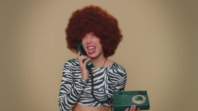 疯狂的女孩，戴着棕色郁郁葱葱的假发，在80年代的有线老式电话上聊天，愚弄愚蠢的面孔