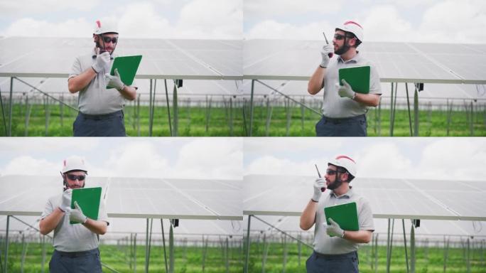 男性太阳能工程师使用对讲机与控制中心官员讨论如何按照太阳能发电厂的维护计划检查太阳能电池板的质量。