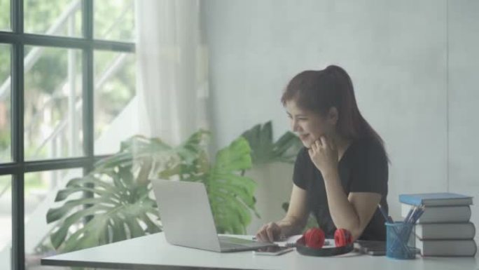 Asian woman wearing headphones with laptop and boo