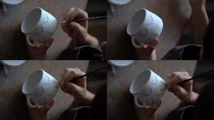 女人喜欢用刷子在白色陶瓷杯上手工制作陶器工艺绘画创意图案