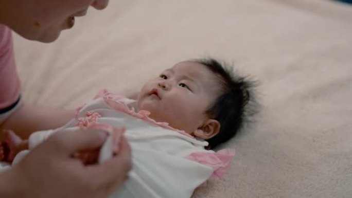 4K，帅气的亚洲爸爸穿着粉色衬衫，和宝贝女儿躺着调侃，在一张柔软的棕色床上，爸爸温柔地邀请小男孩说话
