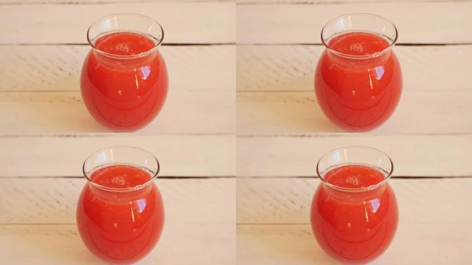 用成熟的西瓜果肉制成的带有红色西瓜饮料的玻璃器皿站在白色的木制桌子上。复制空间，多莉镜头，俯视图，西