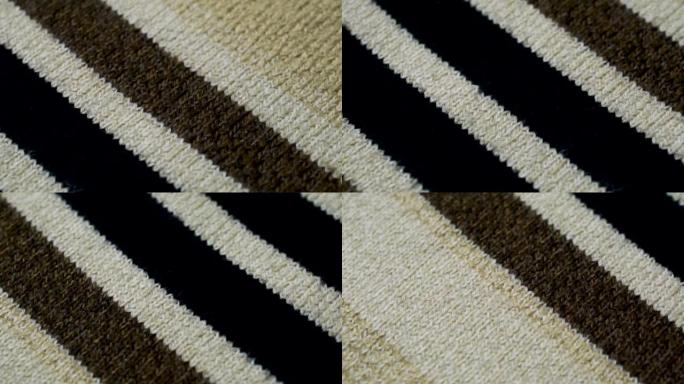 米色针织面料质地，黑色白色和棕色线条。特写细节毛衣面料背景。冬季时尚背景柔软羊毛纺织图案