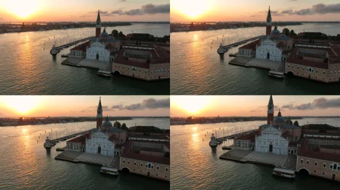 威尼斯群岛圣乔治·马焦雷教堂的空中无人机日出场景和泻湖蓝水之间的船只交通