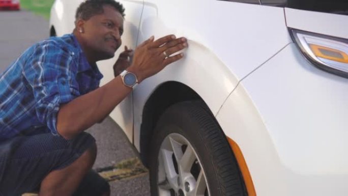 非裔美国人男子看着自己的汽车损坏