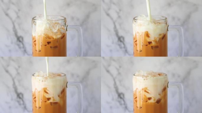 冰牛奶。泰国茶将鲜牛奶倒入玻璃杯中，一种夏季饮料概念